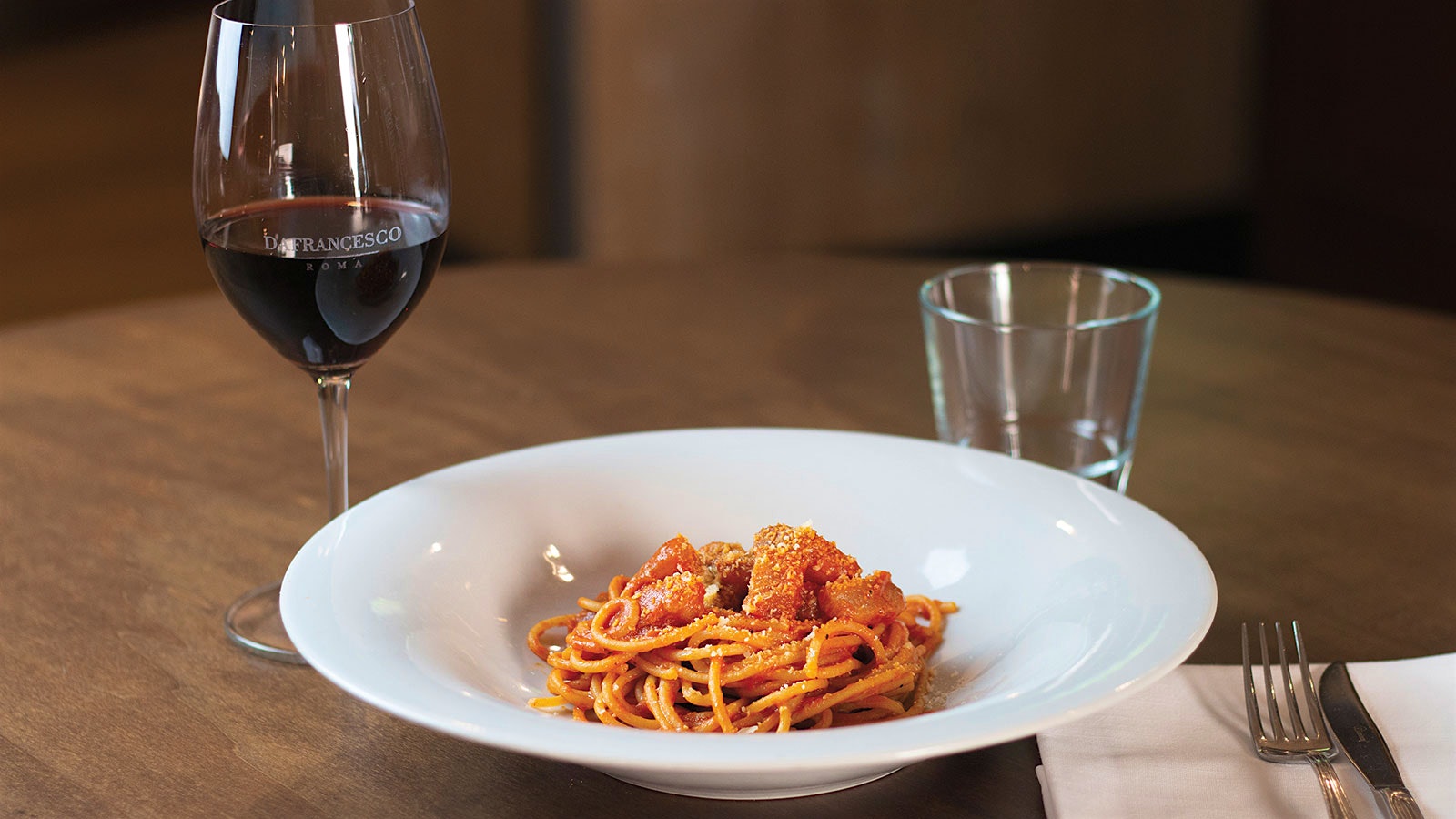 A glass of red wine and a plate of pasta, spaghettoni all’amatriciana at Da Francesco in Rome